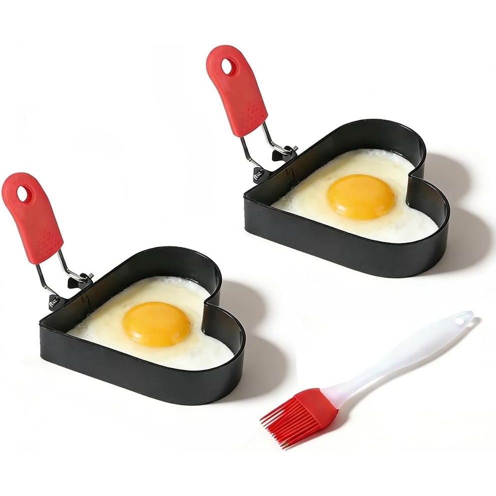 Two black heart-shaped egg rings with red handles and silicone oil brush